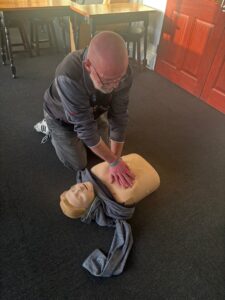 Person providing a demonstration of CPR on a Manikin on the floor