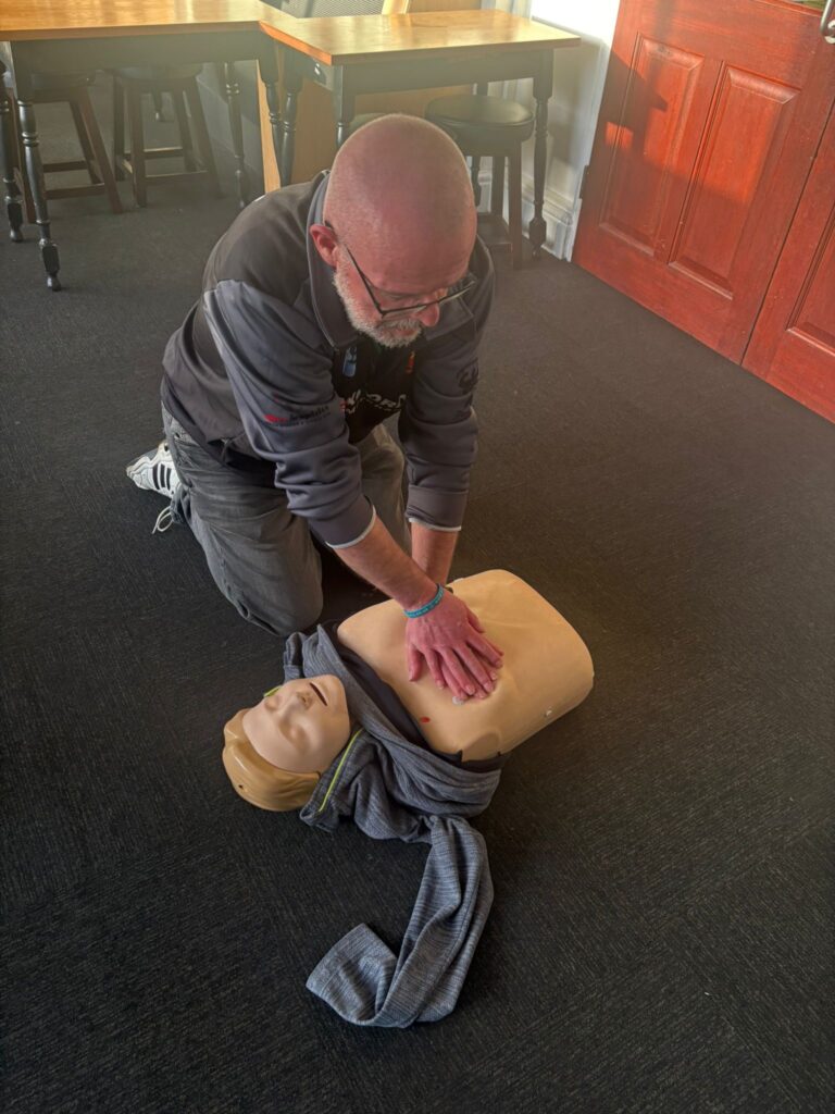 Person providing a demonstration of CPR on a Manikin on the floor